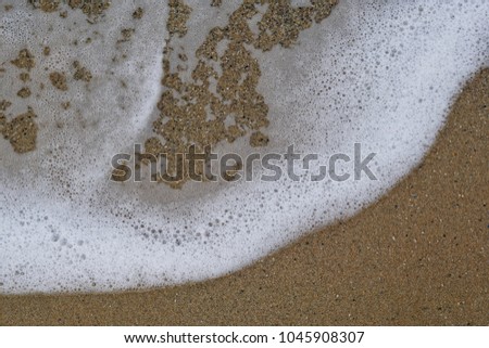 White foam from waves smoothly flushing to sandy beach creating beautiful soft patterns in crete, greece, macro photography              