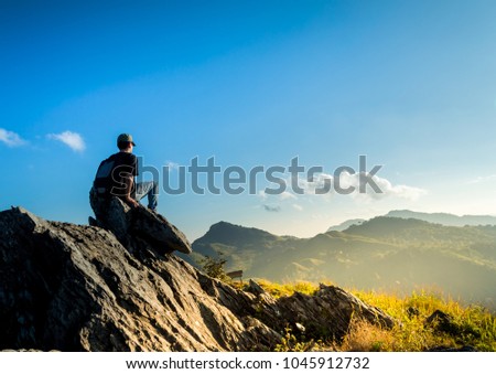 Landscape images vivid fresh bright colorful beautiful nature background And male tourist sitting on a rocky mountain top, called Doi Pha Tang, which is a natural attraction in northern Thailand.
