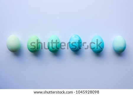 Six speckled and dyed eggs in a row painted gradient shades of blue and green as an Easter DIY family kids arts and crafts activity 