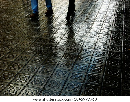 Barcelona. Couple legs and their reflection on wet flower street paving. Romantic vacation background. 