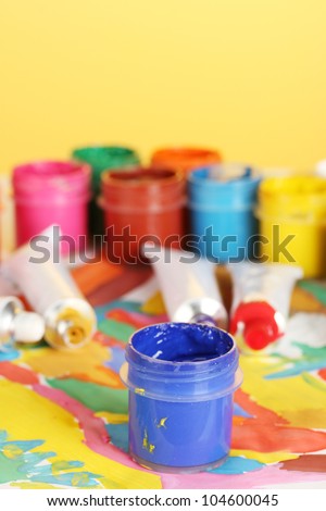 tubes with colorful watercolor and jars with gouache on colorful picture close-up
