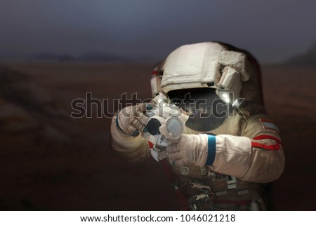 Spaceman with a camera in a space suit on the planet Mars. Astronaut takes pictures a new planet.