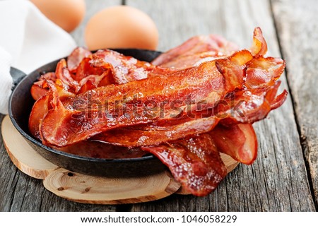 Hot fried bacon pieces in a cast iron skillet.top view Royalty-Free Stock Photo #1046058229