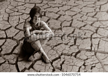 young beautiful girl sits in a desert on a cracked earth Black and white