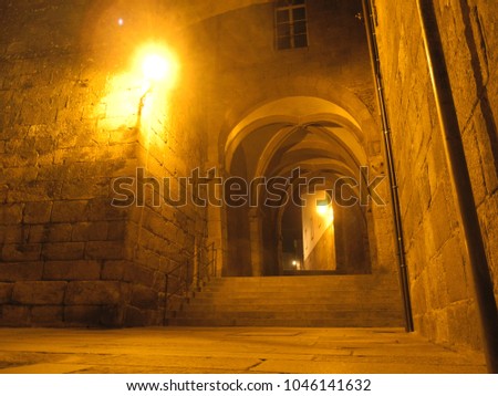 Streets of downtown at night from Santiago de Compostela in Spain. Medieval archway with luminous lanterns at the destination of the Way of St. James. The picture is taken from the worm's-eye view.