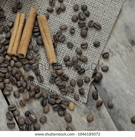 Coffee grains and cinnamon, on cloth and wooden table.