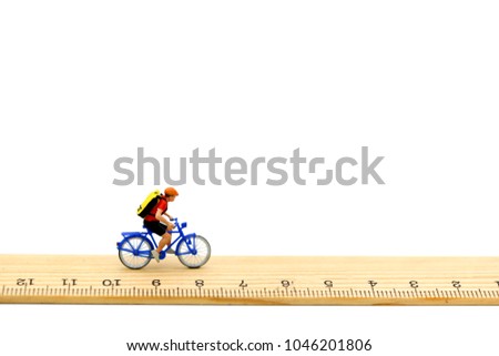 Miniature people : travelers riding bicycle with wooden ruler.