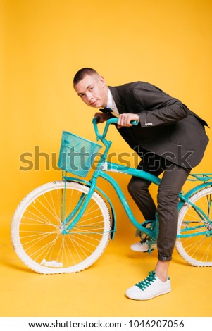 young guy in a business suit riding a colored bike. emotional portrait of a leading wedding celebration or an animator for adults. short haircut and clean skin. concept: tourism and travel by bike