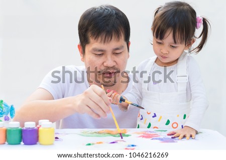 Asian father and cute daughter are playing by color painting together with fully happiness moment on the white background, concept of learning activity for kid in family lifestyle