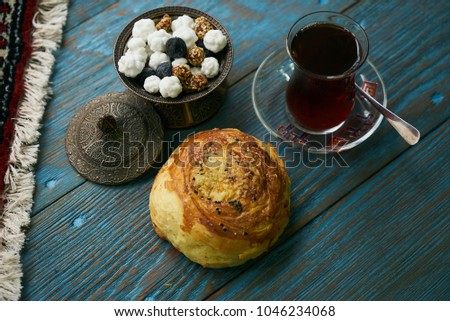 Novruz holiday with Azerbaijan national pastry Gogal and glass of black tea with traditional snack in silver bowl on wooden table background. Delicious dessert holiday food