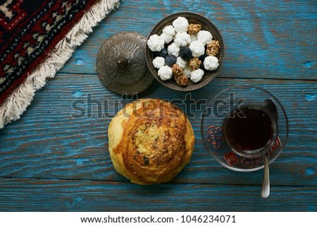 Novruz holiday with Azerbaijan national pastry Gogal and glass of black tea with traditional snack in silver bowl on wooden table background. Delicious dessert holiday food