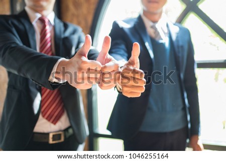 two businessman stand and show thumb up their hand to demonstrating their agreement to sign agreement or contract between their firms companies enterprises. successful concept