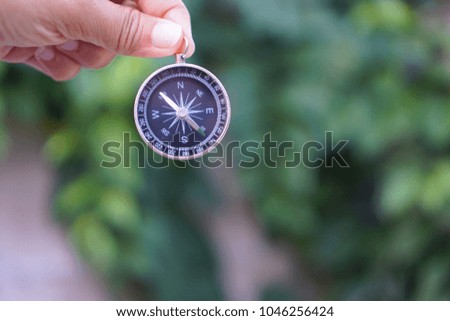Compass in holding hand with green nature blur background