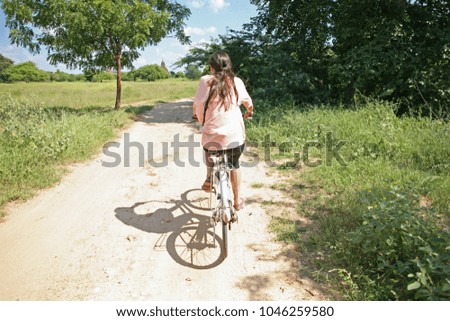 Young female cycles through the countryside of Burma