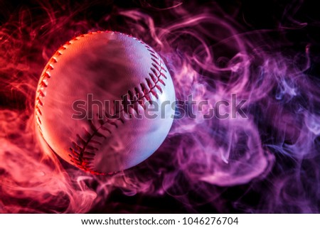 Colorful baseball ball in multi-colored red smoke from a vape on a black isolated background