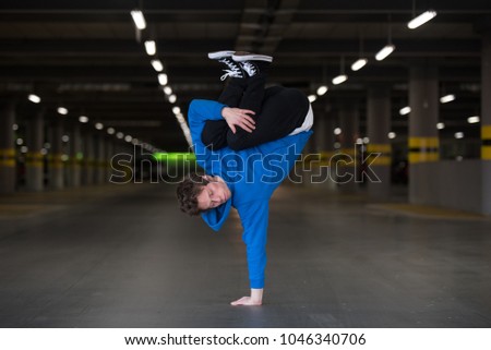 Young man dancing breakdance in the garage.
