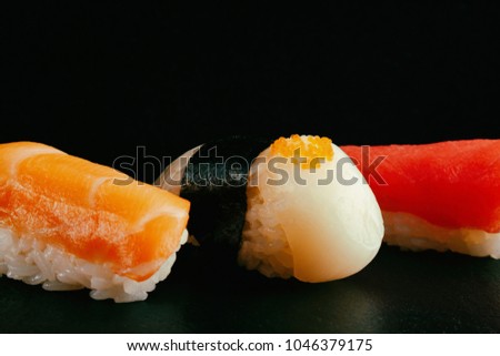 fresh traditional sushi with salmon, scallop and tuna on a black background. beautiful picture of sushi.
