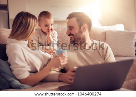 Portrait of a joyful family using a laptop, sitting on sofa at home