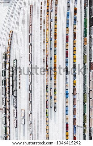 Train depot from above, long colourful train sets, sunny day in winter.