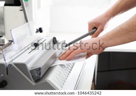 Binding documents, a man binds cards. The bookbinder binds documents. Royalty-Free Stock Photo #1046435242