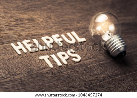 Helpful Tips text with glowing light bulb on wood texture