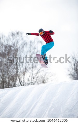 Image of athlete in helmet riding snowboard from snow slope