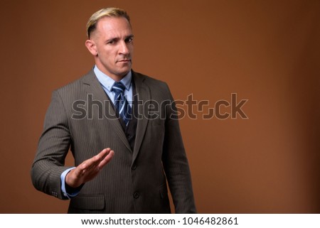Studio shot of businessman wearing suit against brown background