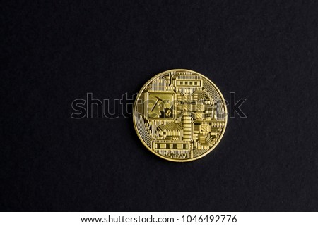 Backside of a physical gold Bitcoin on black background