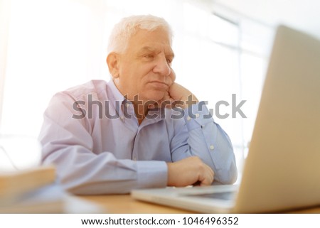 Sad aged man reading e-mails on laptop
