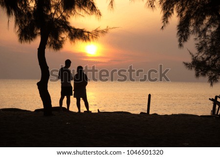 The golden sunset in the morning is orange with lovers are told at a beach.