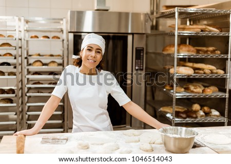 female baker standing at workplace on baking manufacture Royalty-Free Stock Photo #1046514043