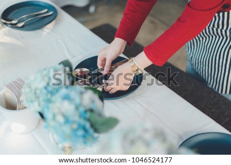 Close up on Asian woman hands, that setting up the table for dinner in urban elegance restaurant. Royalty-Free Stock Photo #1046524177