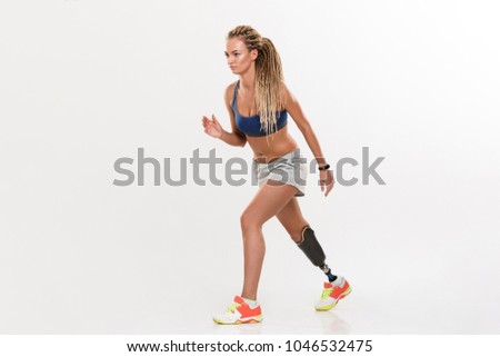 Full length portrait of a healthy young disabled sportswoman running isolated over white background