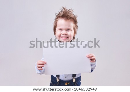 The little boy holds in hand a blank sheet of paper for any purpose