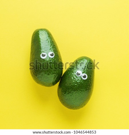 Two funny avocado with eyes on bright yellow background. Top view, concept.