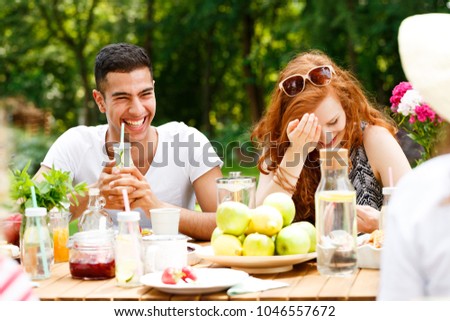 Smiling spanish man drinking water during a meeting with his girlfriend in the park