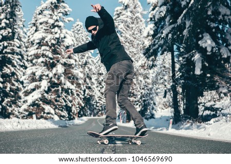 Skateboarder doing powerslide on the icy mountain road in the Winter