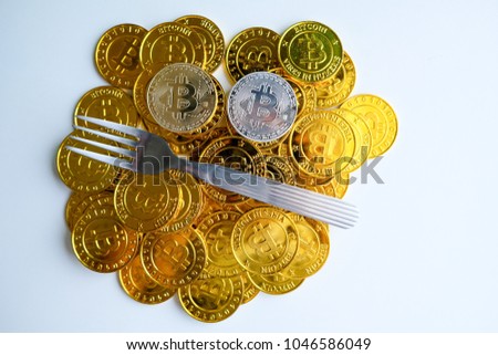 Golden and silver bitcoin with fork on among piles of bitcoin Hard fork change concept