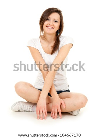 smiling teenage girl sitting on the floor with crossed legs, full length, white background