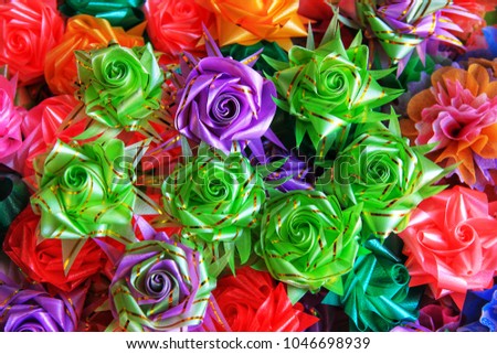 Colorful almsgiving ribbon-flowers. Close up colorful ribbon flowers and coins folding with mulberry paper for giving alms to make merit in Thai's religious traditional. It is a beautiful picture.