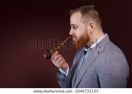 portrait of a red bearded man smoking a pipe on a brown background