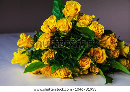 Bouquet of yellow roses is laying on the light wooden table without water