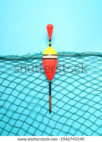 Fishing net with homemade bobber on blue background. Picture with space for your text.