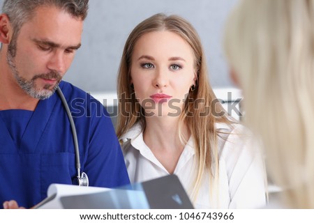 Smiling handsome doctor communicate with patient holding silver pen and showing pad. Physical agreement signature disease prevention interpreter translator prescribe remedy healthy lifestyle