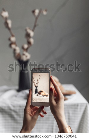 Hands of unrecognisable woman taking photo of bread on dining table.