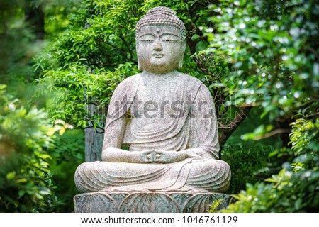 Buddha statue in the garden with green trees in the background