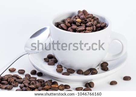 Coffee espresso cup and saucer with fresh roasted coffee beans on a plain white background