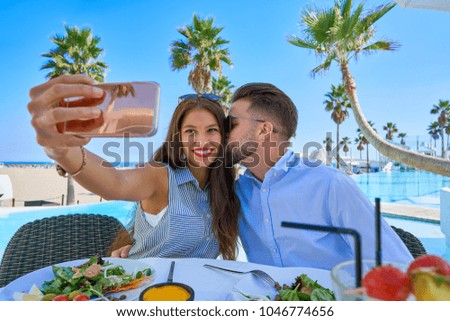 Young couple selfie smartphone photo in a swimming pool restaurant