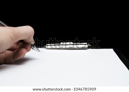 A horizontal photo of a black clipboard with a pen ready to write
