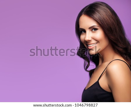 Portrait of beautiful smiling young woman in black top clothing, on violet background, with blank copyspace area for slogan or text